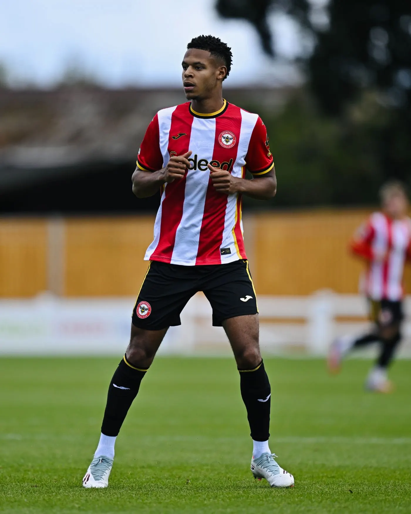 Kaye Furo standing on the pitch in the Brentford home kit. He is 1.90 m tall and right-footed.